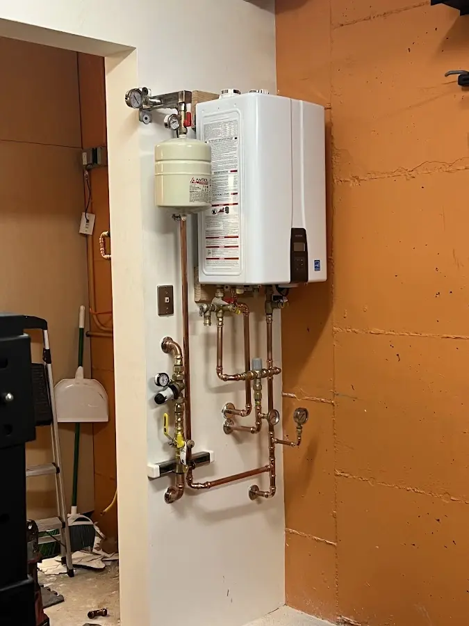 Plumbing technician inspecting water heater connections in Bellefonte